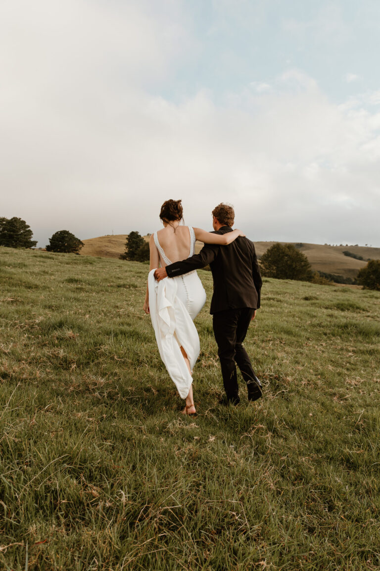Cotswold wedding photographer - bride and groom walking in the fields at their Cotswold farm wedding