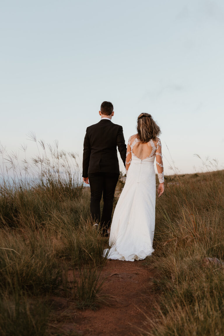 Bride and groom walking hand-in-hand at their Cotswold countryside wedding